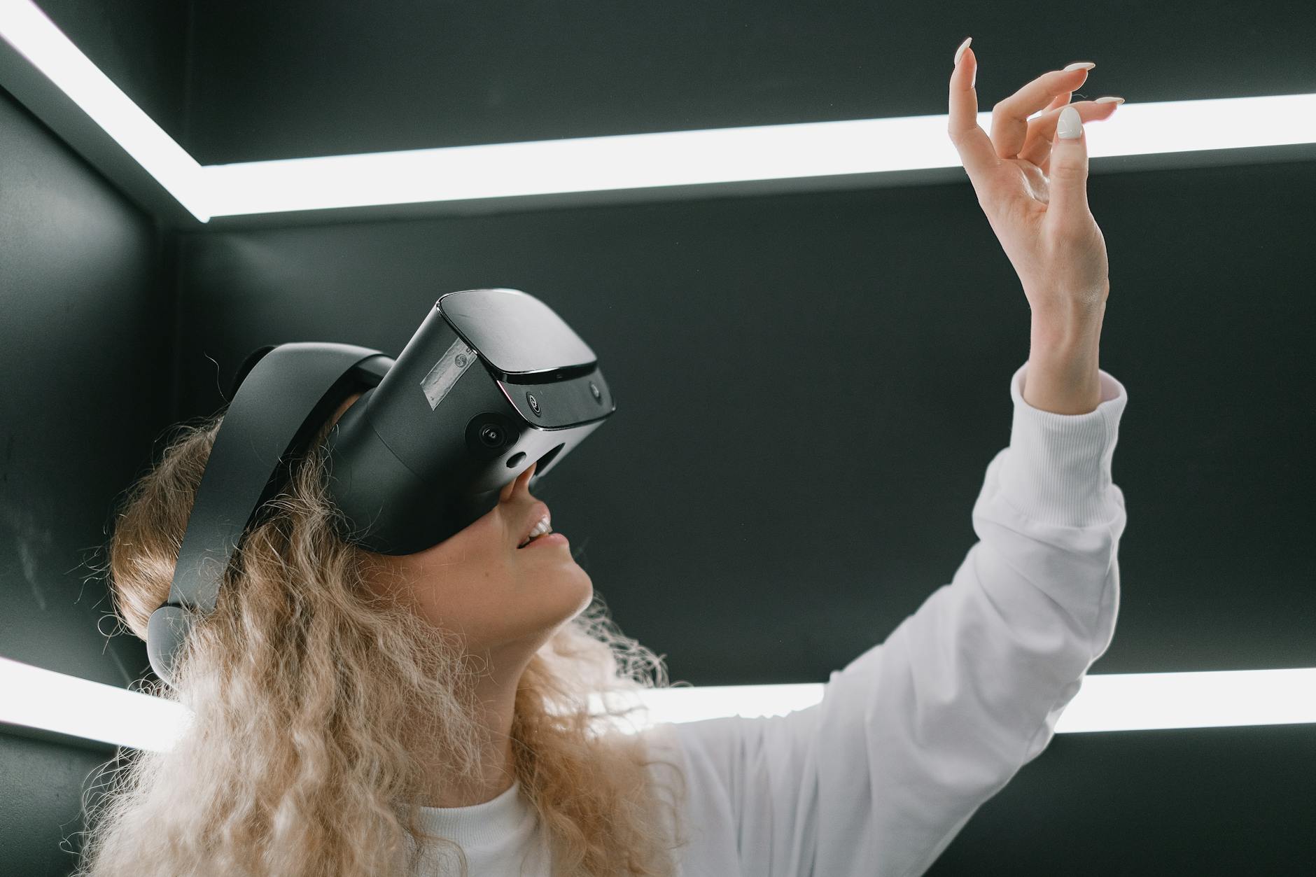 celebrity tech trends - A woman wearing a headset engages with virtual reality, reaching out her hand.