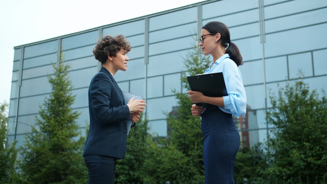 leo brooks andrew millsaps - Two businesswomen talking outside modern building