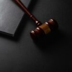 why pardon netanyahu - Wooden gavel resting on a dark surface next to book