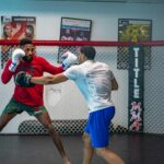 why dana white sold ufc - Two men engaged in an intense mixed martial arts training in an indoor gym.